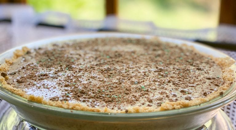 A delicious Peppermint Crisp Tart, with layers of creamy filling, crumbled biscuit, and peppermint chocolate topping.