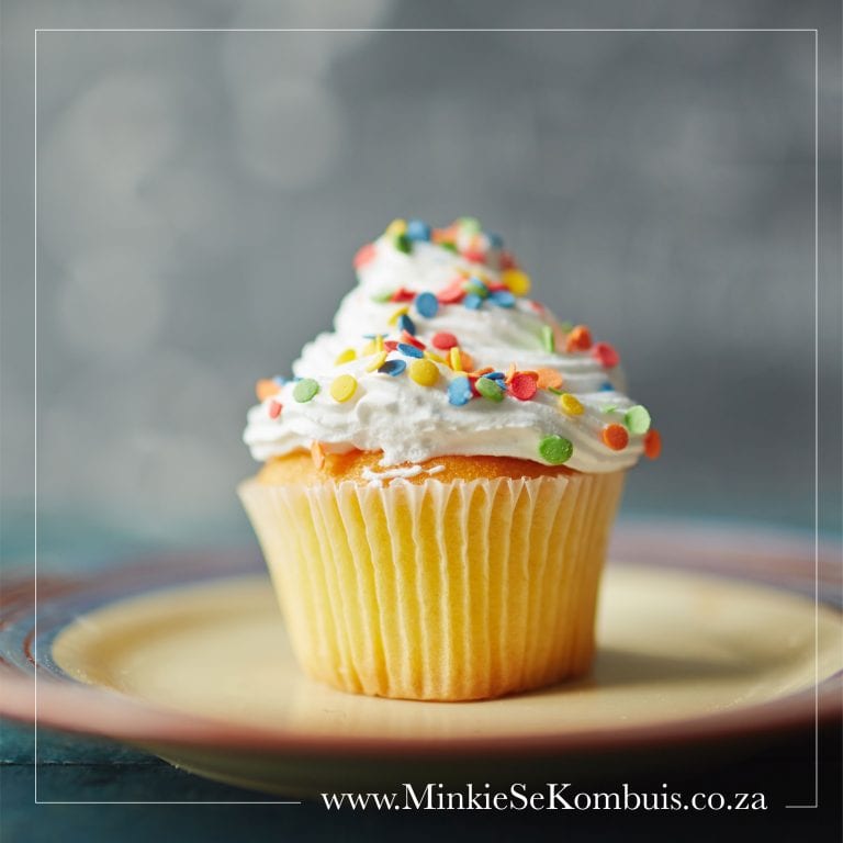 A delicious cupcake with a swirl of frosting on top, decorated with sprinkles and a colorful wrapper.